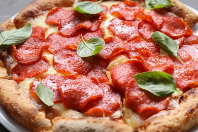 Tasty pepperoni pizza with basil on table, closeup