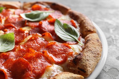 Tasty pepperoni pizza with basil on grey table, closeup