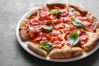 Photo of Tasty pepperoni pizza with basil on grey table