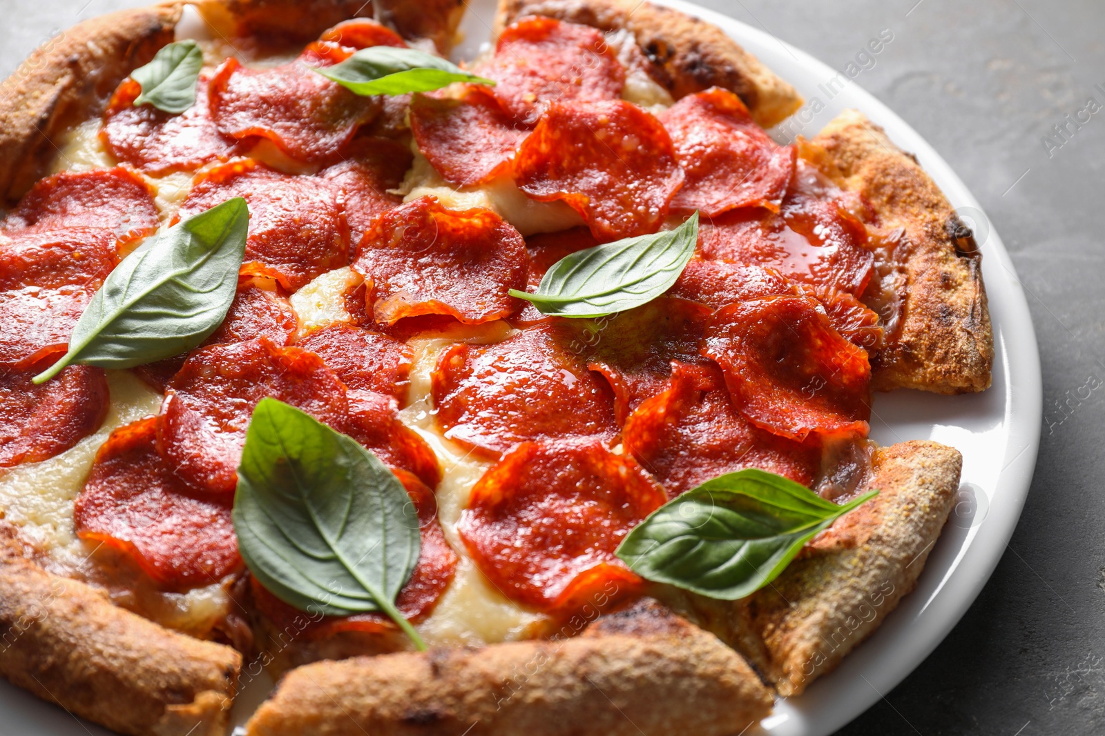 Photo of Tasty pepperoni pizza with basil on grey table, closeup