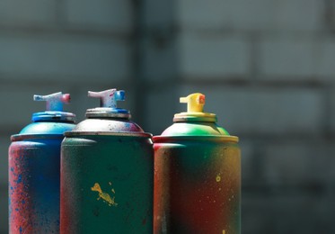 Many spray paint cans against blurred background, closeup. Space for text