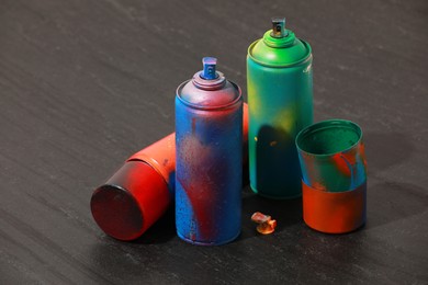 Many spray paint cans on gray textured surface