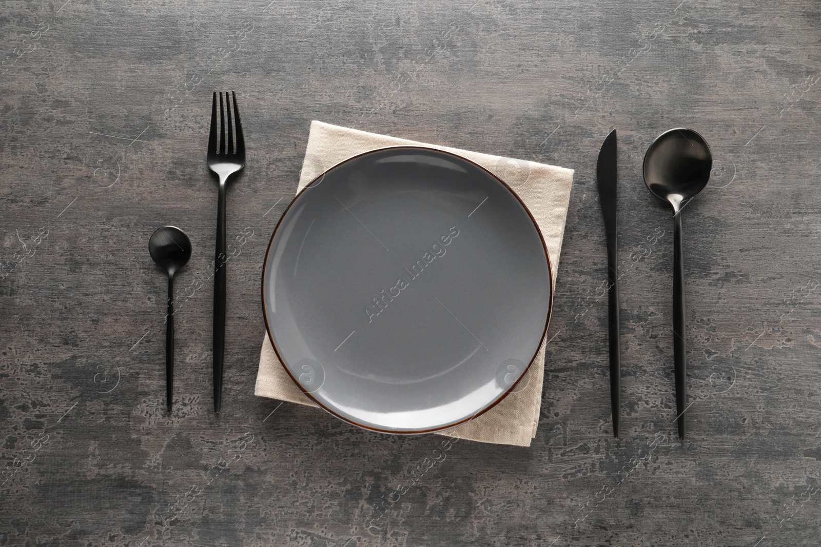 Photo of Stylish cutlery, plate and napkin on grey table, flat lay