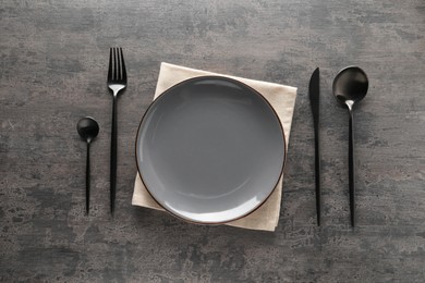 Stylish cutlery, plate and napkin on grey table, flat lay