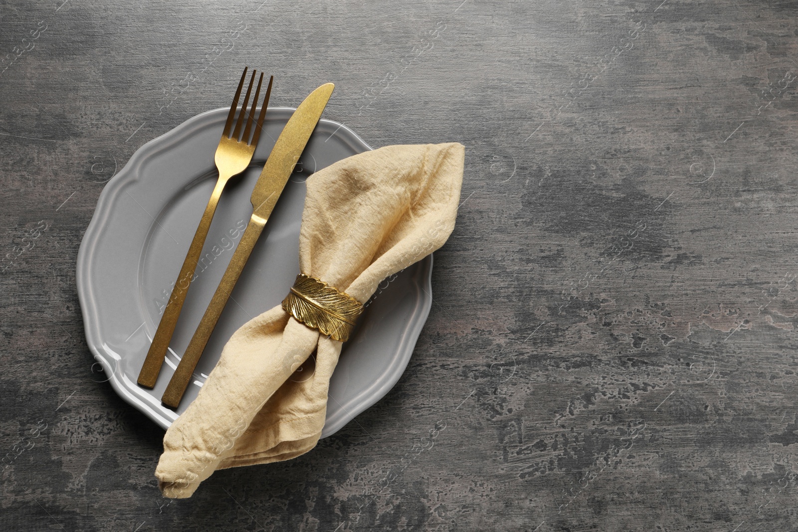 Photo of Stylish cutlery, plate and napkin on grey table, top view. Space for text