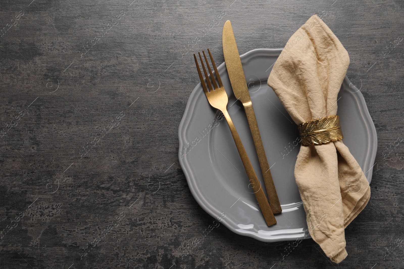 Photo of Stylish cutlery, plate and napkin on grey table, top view. Space for text