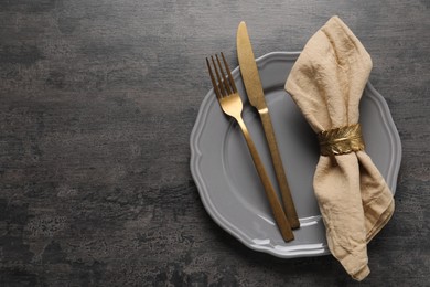 Photo of Stylish cutlery, plate and napkin on grey table, top view. Space for text