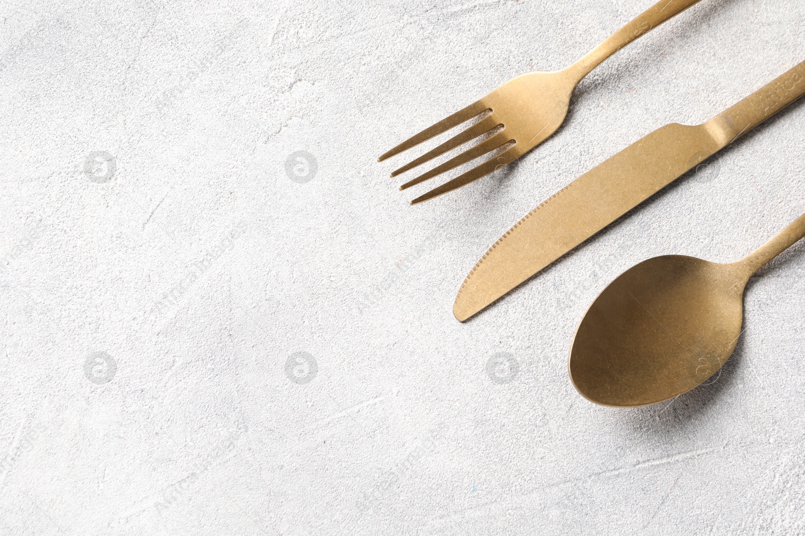 Photo of Stylish cutlery on light grey table, above view. Space for text