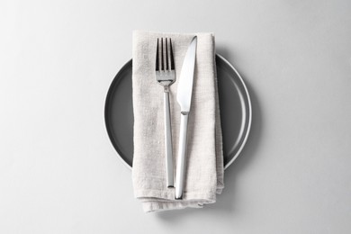 Photo of Stylish silver cutlery, plate and napkin on white background, top view