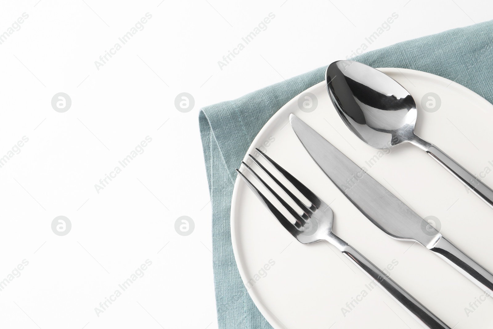 Photo of Stylish silver cutlery, plate and napkin on white background, top view. Space for text