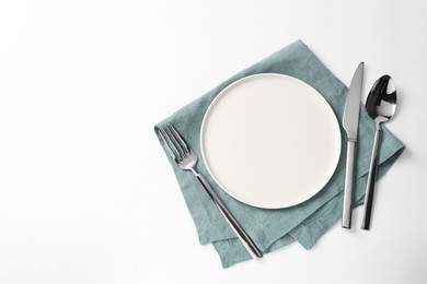 Photo of Stylish silver cutlery, plate and napkin on white background, top view. Space for text