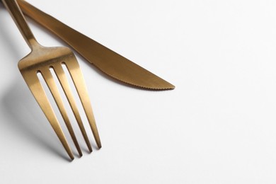 Photo of Stylish golden cutlery on white background, closeup. Space for text