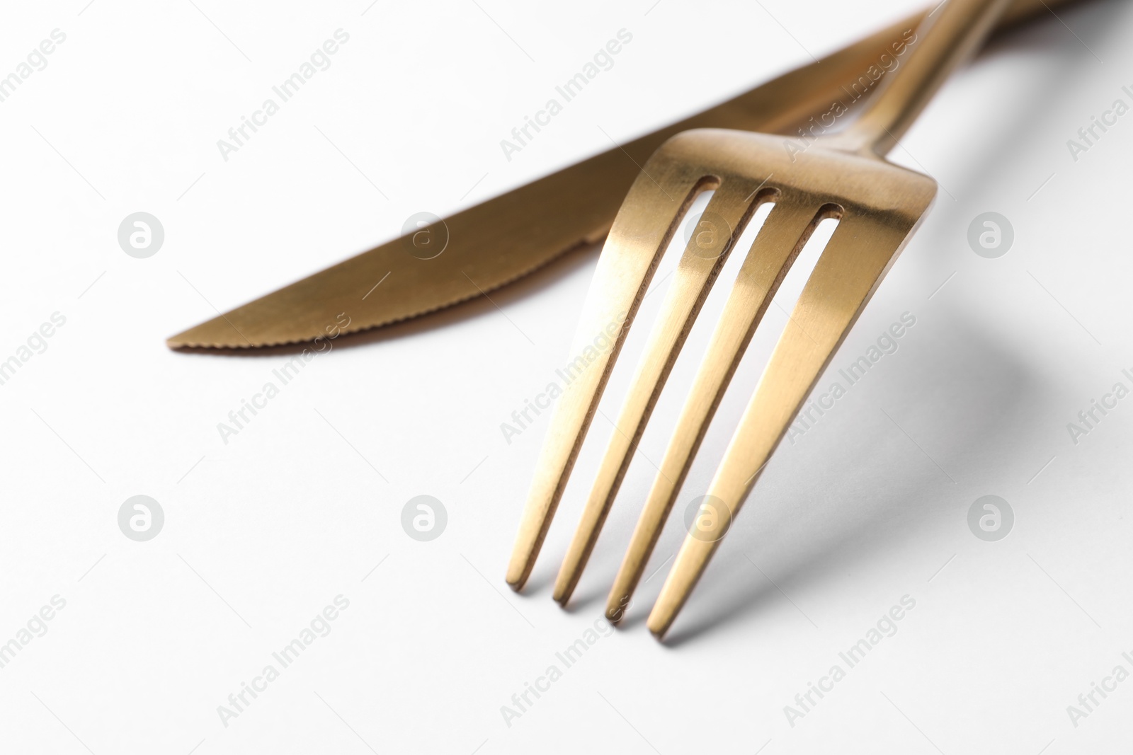 Photo of Stylish golden cutlery on white background, closeup