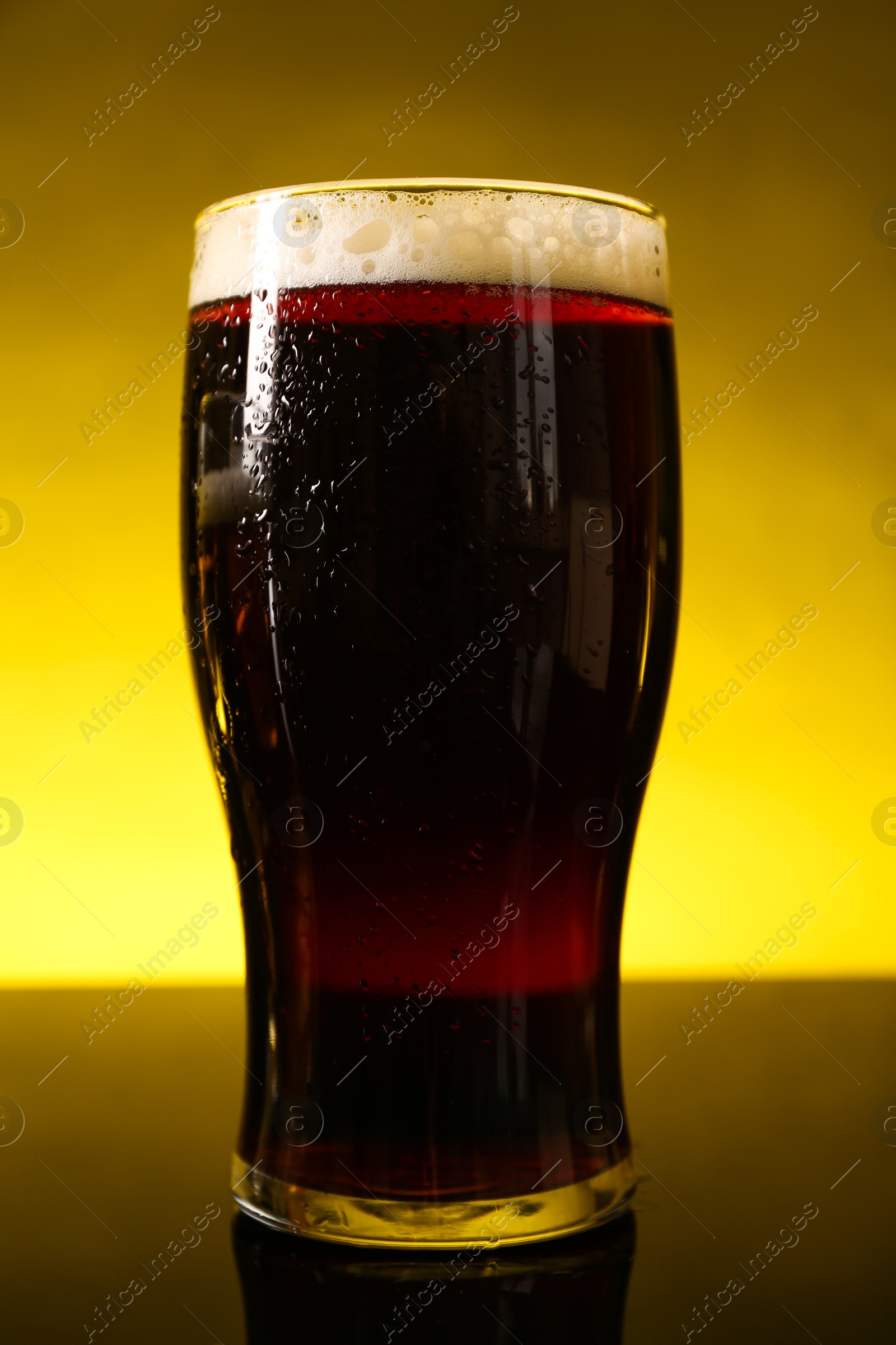 Photo of Glass of beer with froth on dark table, closeup