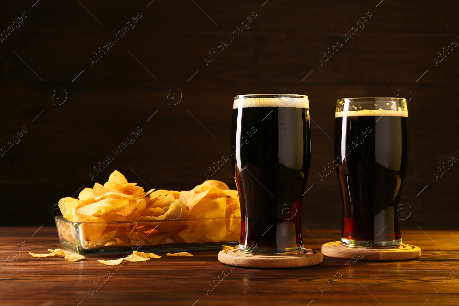 Photo of Glasses of beer and potato chips on wooden table