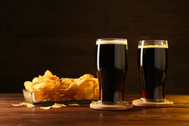 Photo of Glasses of beer and potato chips on wooden table