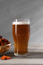 Glass of beer and rusks on grey wooden table