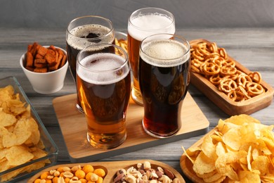 Photo of Glasses with different types of beer and snacks on grey wooden table