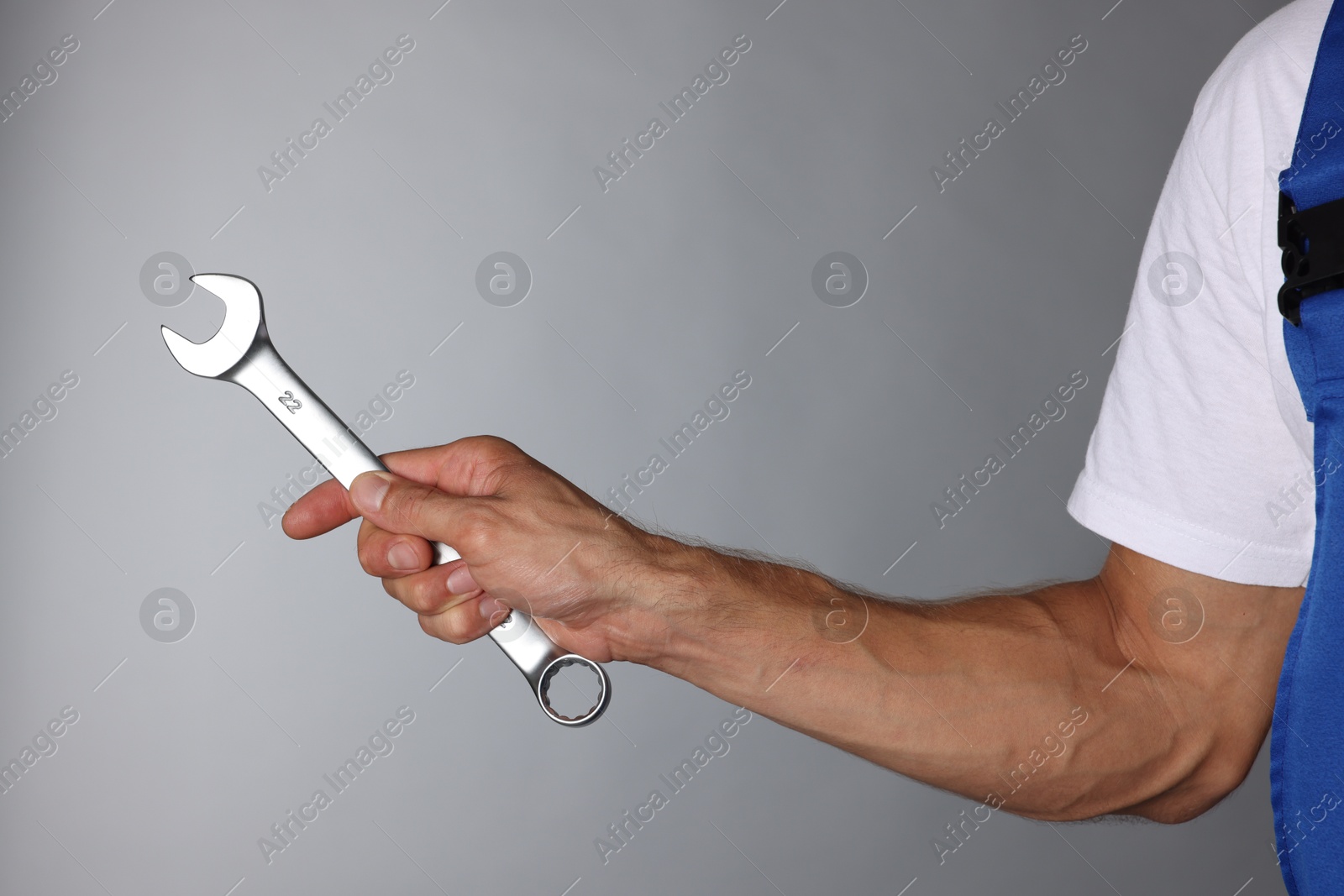 Photo of Auto mechanic with wrench on grey background, closeup