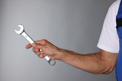 Photo of Auto mechanic with wrench on grey background, closeup