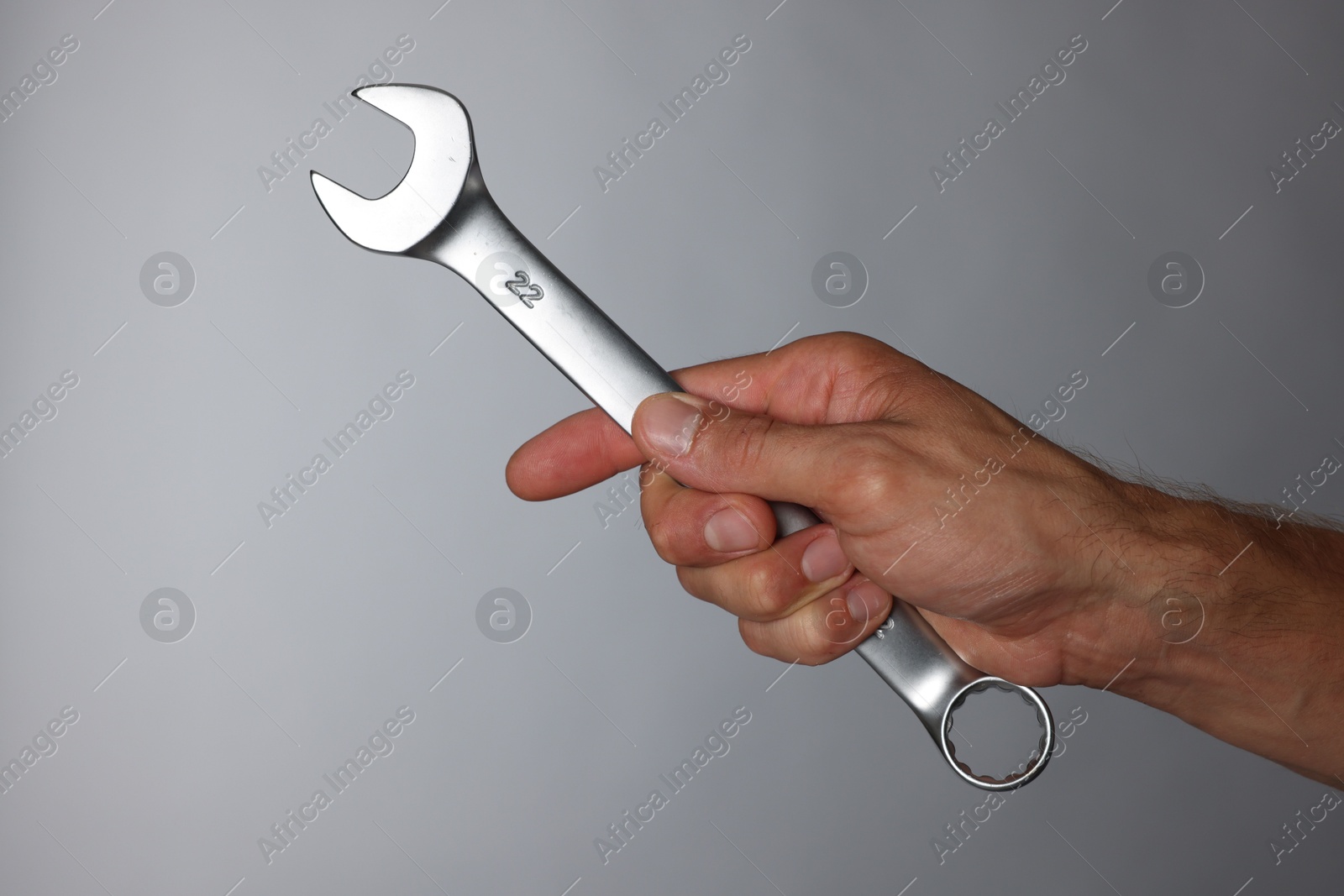 Photo of Auto mechanic with wrench on grey background, closeup