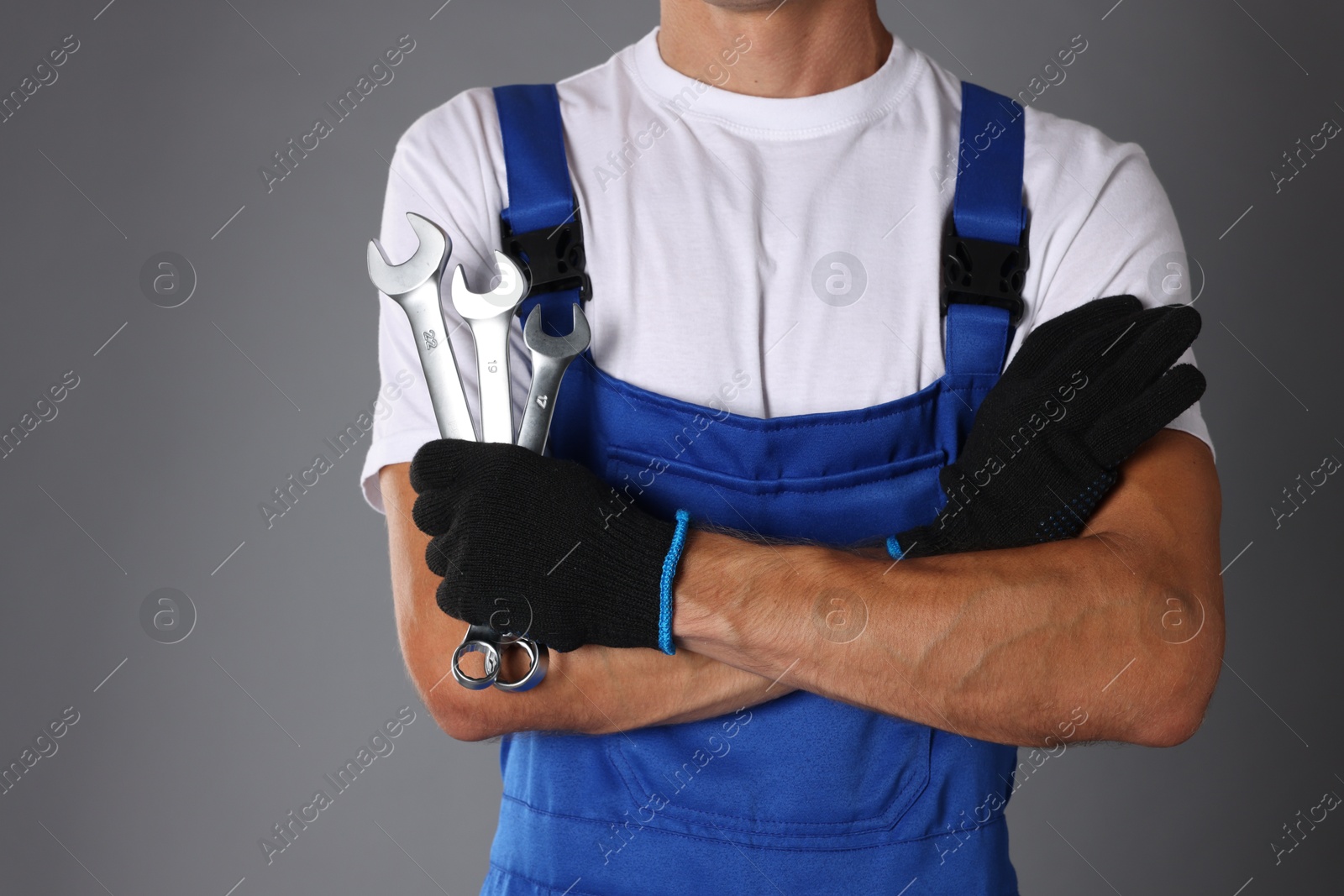 Photo of Auto mechanic with wrenches on grey background, closeup