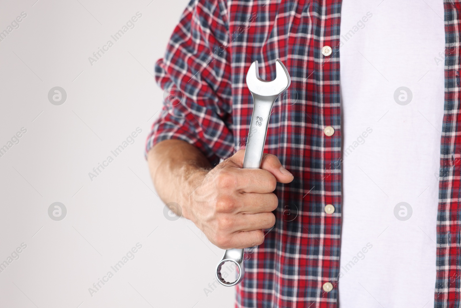 Photo of Auto mechanic with wrench on light grey background, closeup. Space for text