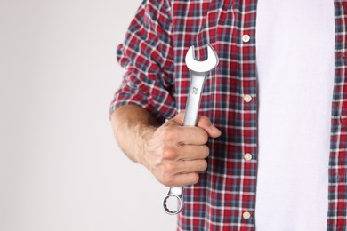 Photo of Auto mechanic with wrench on light grey background, closeup. Space for text