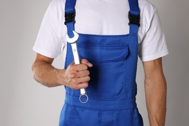 Photo of Auto mechanic with wrench on light grey background, closeup