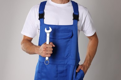 Auto mechanic with wrench on light grey background, closeup