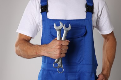 Photo of Auto mechanic with wrenches on light grey background, closeup