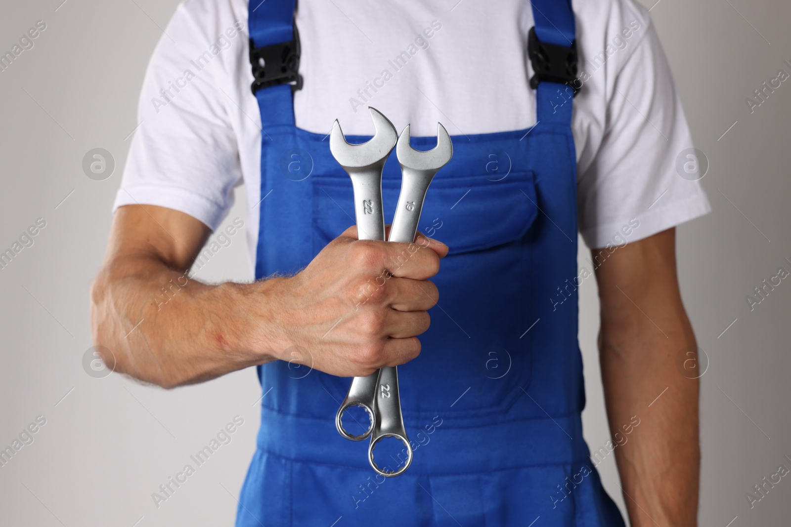 Photo of Auto mechanic with wrenches on light grey background, closeup