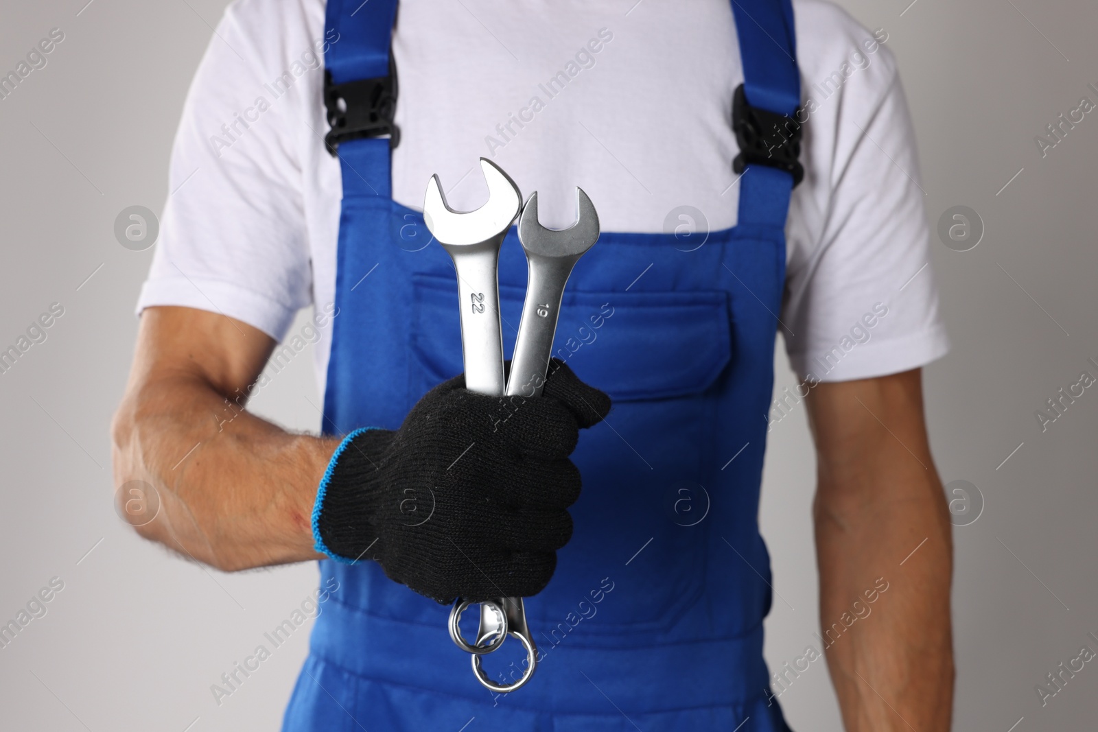 Photo of Auto mechanic with wrenches on light grey background, closeup