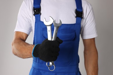 Photo of Auto mechanic with wrenches on light grey background, closeup