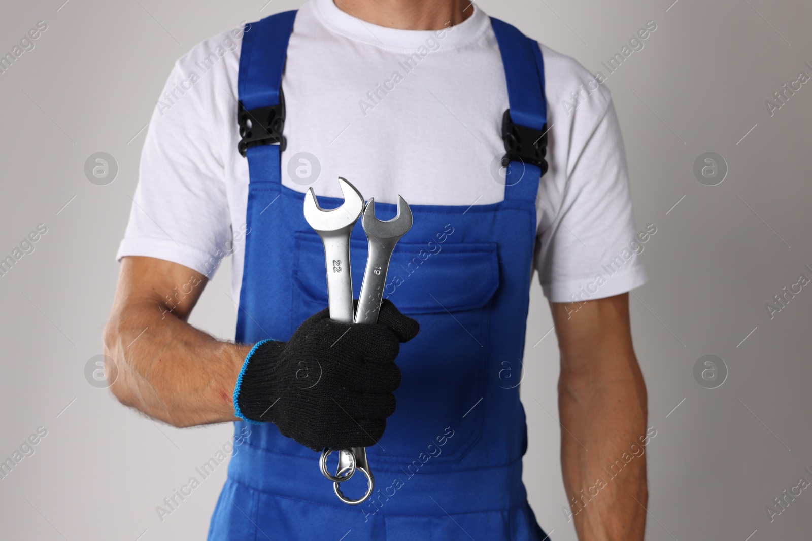 Photo of Auto mechanic with wrenches on light grey background, closeup