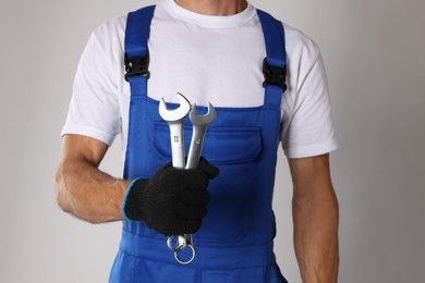 Photo of Auto mechanic with wrenches on light grey background, closeup