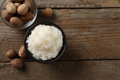 Natural shea butter in bowl and nuts on wooden table, top view. Space for text