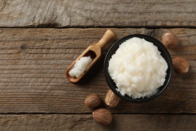 Natural shea butter in bowl and nuts on wooden table, top view. Space for text