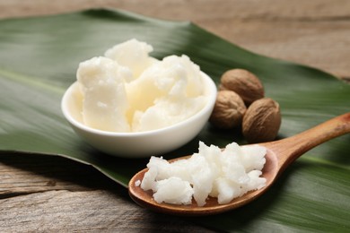 Photo of Natural shea butter, nuts and green leaf on wooden table