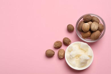 Natural shea butter in bowl and nuts on pink background, top view. Space for text