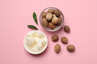 Natural shea butter in bowl, nuts and green leaves on pink background, flat lay