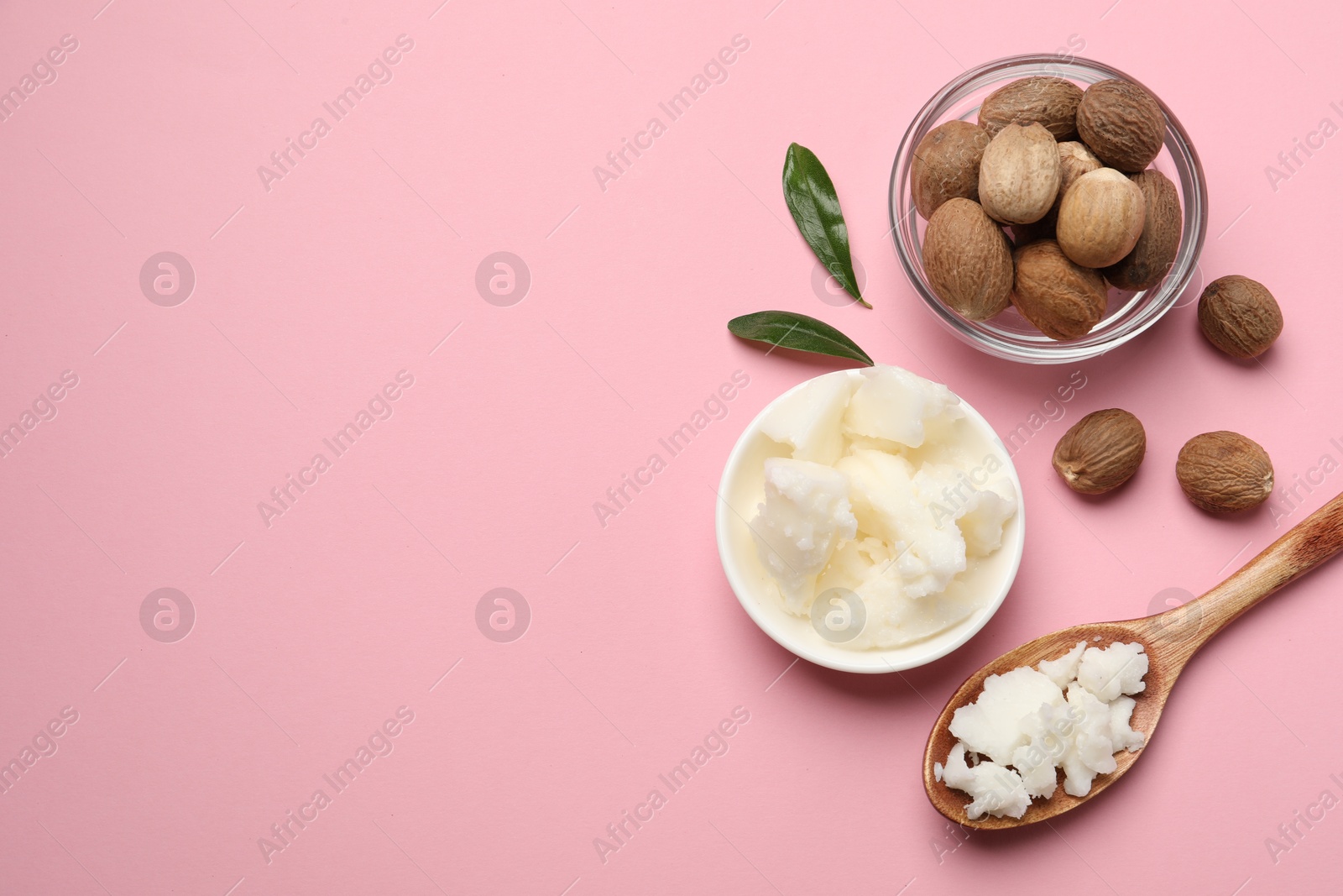 Photo of Natural shea butter in bowl, spoon and nuts on pink background, flat lay. Space for text