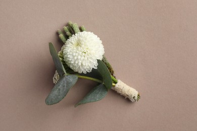 Small stylish boutonniere on beige background, top view