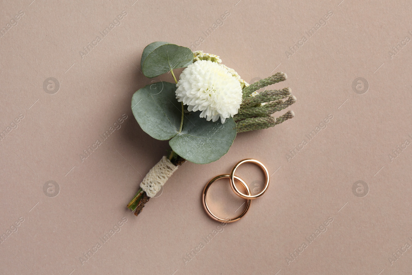 Photo of Small stylish boutonniere and rings on beige background, top view