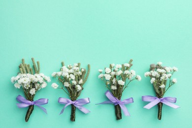 Many stylish boutonnieres on turquoise background, flat lay