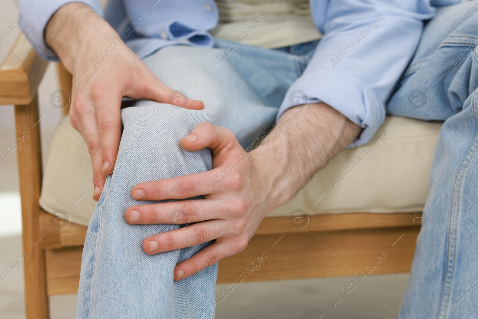 Photo of Man suffering from knee pain in armchair indoors, closeup