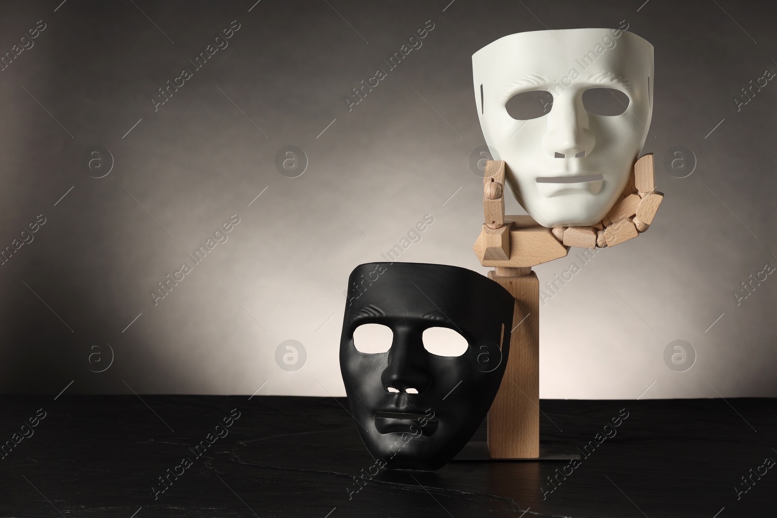 Photo of Wooden mannequin hand and plastic masks on color background, space for text. Theatrical performance