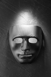 Plastic face mask on black slate surface, top view. Theatrical performance