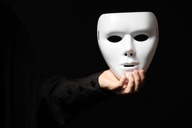 Photo of Theatrical performance. Man holding plastic mask on black background, closeup