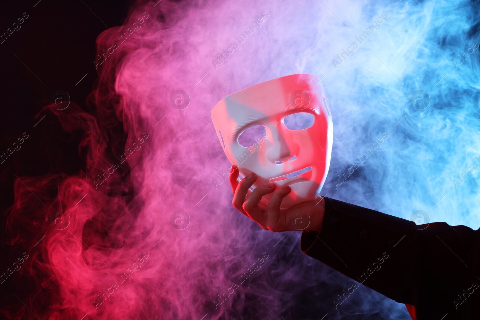 Photo of Theatrical performance. Man with plastic mask in smoke on dark background, closeup. Space for text